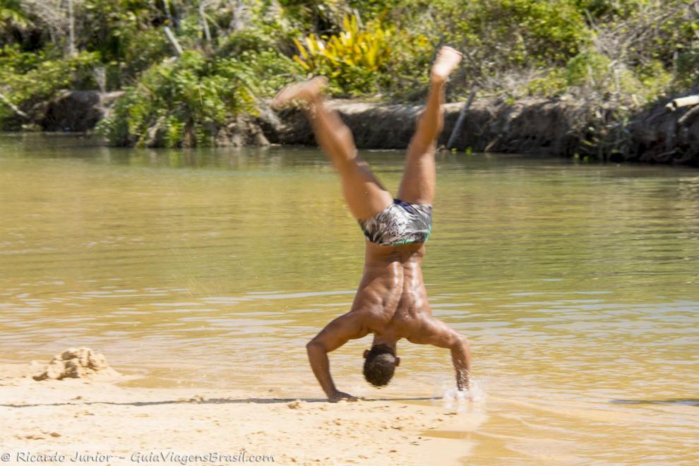 Imagem de um rapaz fazendo piruetas na piscina natural da Praia de Pitinga.